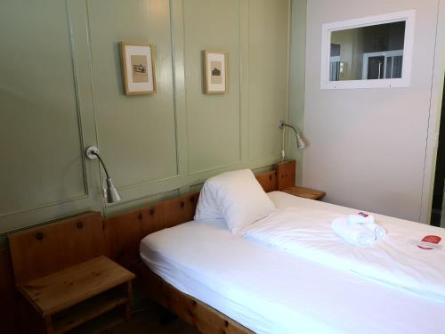 a small bedroom with a white bed and a mirror at Historisches Hotel Piz Ela Bergün in Bergün