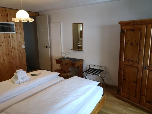 a bedroom with two beds and a dresser and a mirror at Historisches Hotel Piz Ela Bergün in Bergün