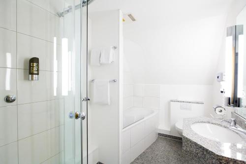 uma casa de banho branca com um lavatório e um chuveiro em Hotel Schützenhof em Eitorf