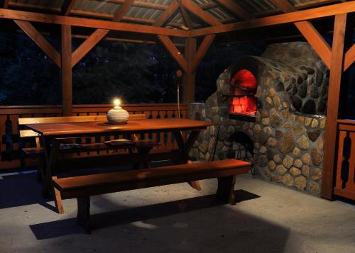 a wooden table and bench with a candle on a patio at Leśny Dworek in Kryłatka