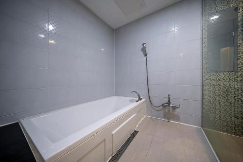 a white bathroom with a tub and a shower at Hotel Cullinan Yongin in Yongin
