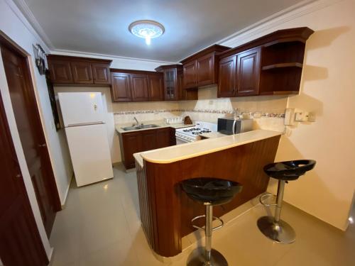 a kitchen with wooden cabinets and a white refrigerator at 1Dom Rep - Huge cozy 3 bedrooms - close to all transportation Jacobo Majluta - Residencial Paradise V Colina Arroyo 1 in Santo Domingo