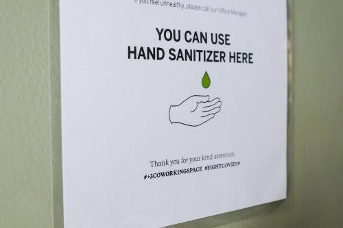 a poster on a wall with a hand holding a greendrop at Social Hub by TwoSpaces in Jakarta