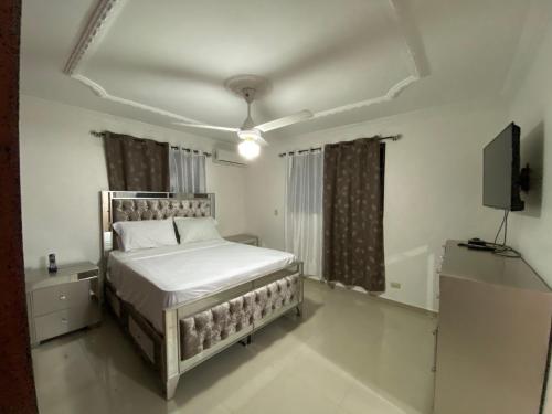 a bedroom with a bed and a flat screen tv at 1Dom Rep - Huge cozy 3 bedrooms - close to all transportation Jacobo Majluta - Residencial Paradise V Colina Arroyo 1 in Santo Domingo
