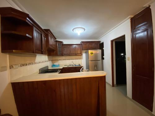 a kitchen with wooden cabinets and a sink and a refrigerator at 1Dom Rep - Huge cozy 3 bedrooms - close to all transportation Jacobo Majluta - Residencial Paradise V Colina Arroyo 1 in Santo Domingo