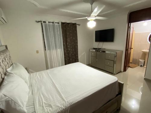 a bedroom with a white bed and a television at 1Dom Rep - Huge cozy 3 bedrooms - close to all transportation Jacobo Majluta - Residencial Paradise V Colina Arroyo 1 in Santo Domingo