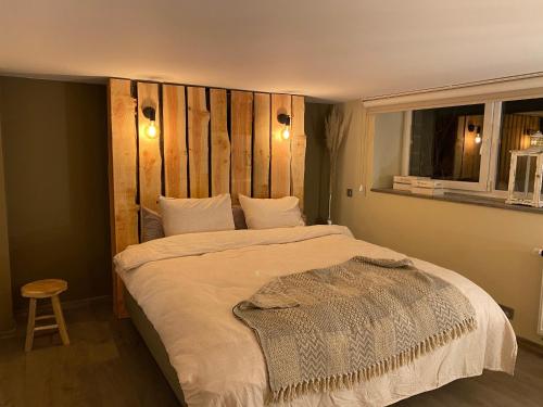 sypialnia z dużym łóżkiem z drewnianym zagłówkiem w obiekcie Le Retour aux Sources - Chambre d'Hôte chaleureuse et conviviale w mieście Chaudfontaine