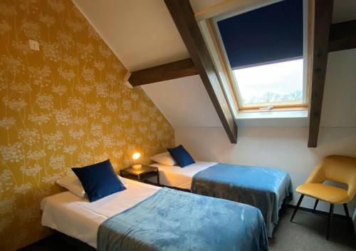 a room with two beds and a window and a chair at Hotel Hof van 's Gravenmoer in 's-Gravenmoer