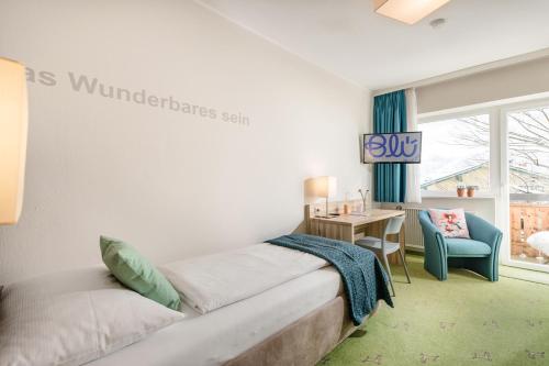 a bedroom with a bed and a desk and a window at Hotel Blü Gastein in Bad Hofgastein