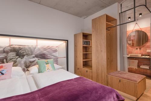a bedroom with a large bed with a purple blanket at Hotel Blü Gastein in Bad Hofgastein