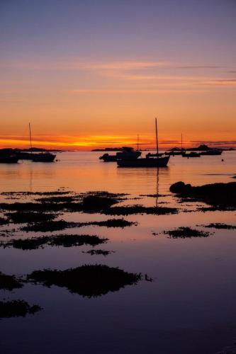 a group of boats sitting in the water at sunset at Résidence CoatArmor in Tonquédec