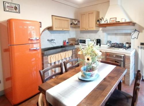 eine Küche mit einem Holztisch und einem orangen Kühlschrank in der Unterkunft Le Melodie Di Lucca in Lucca