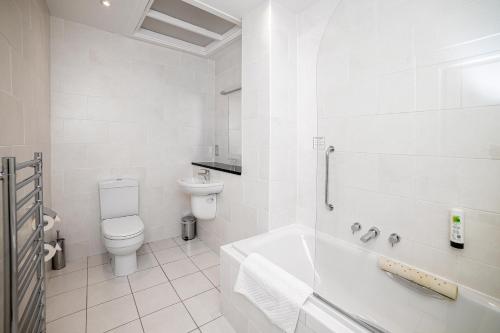 La salle de bains blanche est pourvue de toilettes et d'une baignoire. dans l'établissement The Inn @ Aird a' Bhasair, à Ardvasar