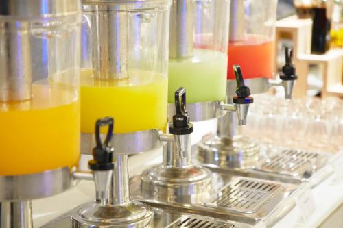 a row of glasses filled with orange and green drinks at The Quarter Ploenchit by UHG in Bangkok