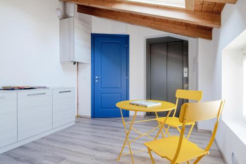 a kitchen with a yellow table and chairs and a blue door at Spazio 77 - The House Of Travelers in Como
