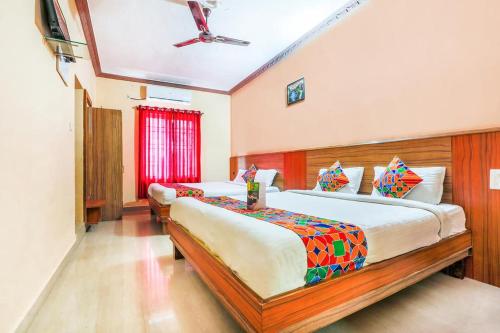 a bedroom with two beds and a ceiling fan at Hotel City Comforts in Madikeri