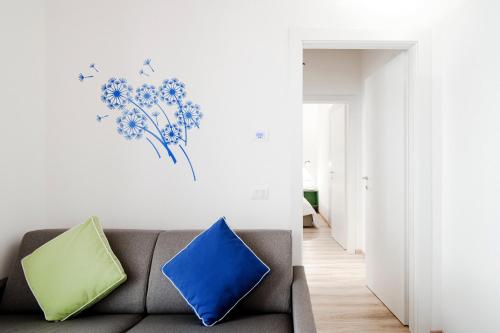 a living room with a couch with birds and flowers on the wall at Spazio 77 - The House Of Travelers in Como