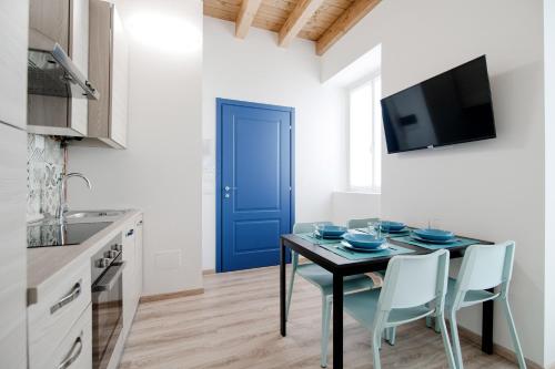 a kitchen with a table with chairs and a blue door at Spazio 77 - The House Of Travelers in Como