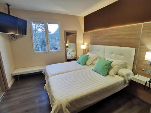 a bedroom with a large white bed with green pillows at Hotel Restaurant Rose des Pyrénées in Belvianes-et-Cavirac