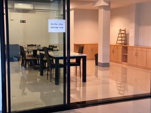 a dining room with a table and chairs and a sign on the window at J2 Residence Chiang Rai in Chiang Rai
