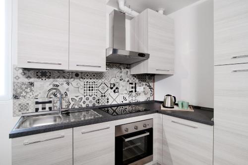 a kitchen with white cabinets and a sink at Spazio 77 - The House Of Travelers in Como
