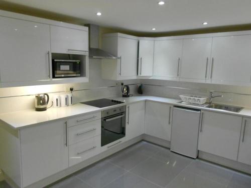 Una cocina blanca con gabinetes y electrodomésticos blancos. en Mapesbury Hostel London, en Londres