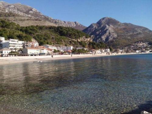 a beach with a town and mountains in the background at Apartments Holiday Lux in Sutomore
