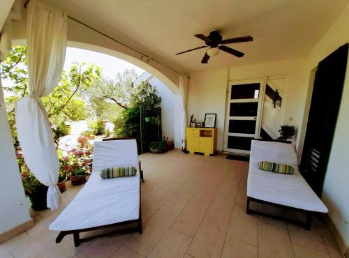 a patio with two beds and a ceiling fan at Holiday Home Subasic in Zlarin