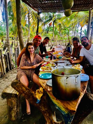 a group of people sitting around a table eating food at Playa Jaguar - Beach Club in Moñitos