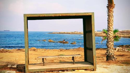 a bench sitting on the beach near the ocean at Dahan Sirena lighthouse Luxury Apartment in Paphos