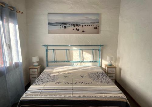 ein Bett in einem Schlafzimmer mit einem Bild vom Strand in der Unterkunft SAN TEODORO PUNTA EST AMPIO TRILOCALE VISTA MARe in Capo Coda Cavallo