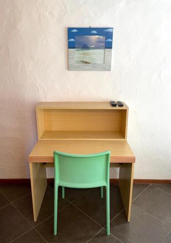 a desk with a green chair next to a wall at SAN TEODORO PUNTA EST AMPIO TRILOCALE VISTA MARe in Capo Coda Cavallo