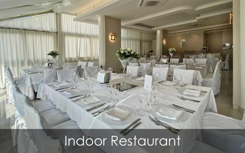 a large dining room with white tables and chairs at Hotel Olimpico in Pontecagnano