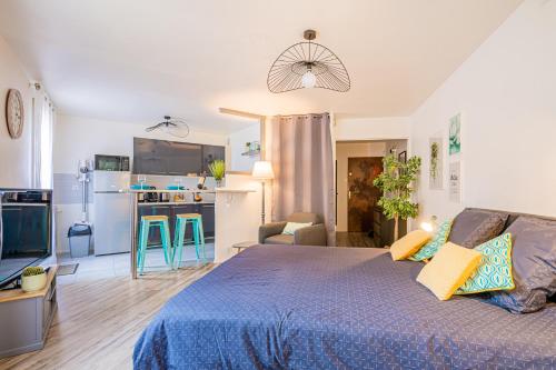 une chambre avec un lit bleu et une cuisine dans l'établissement LE LAGON BLEU - Parking - Netflix - Loggia, Évry-Courcouronnes