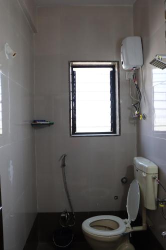 a bathroom with a toilet and a window at Nature's Lap Homestay in Igatpuri