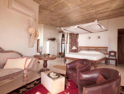 a bedroom with a bed and a couch and chairs at The Majlis Resort in Lamu