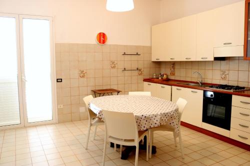 サン・ヴィート・ロ・カーポにあるBluvacanze Appartamento La Sala Immacolataのキッチン(テーブル、椅子付)、キッチン(白いキャビネット付)