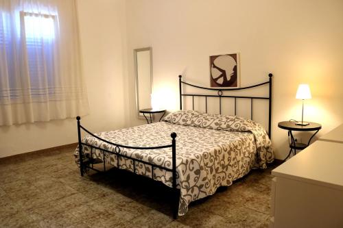 サン・ヴィート・ロ・カーポにあるBluvacanze Appartamento La Sala Immacolataのベッドルーム1室(ベッド1台、テーブル2台、窓付)