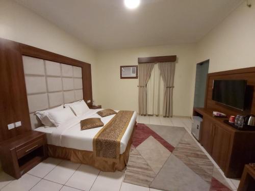 a bedroom with a large bed and a television at Reef Al-Hijrah Furnished Apartments in Al Madinah