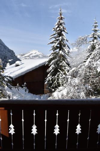 a view of a snow covered mountain with a tree at Chalet le Petit Ramoneur in Châtel