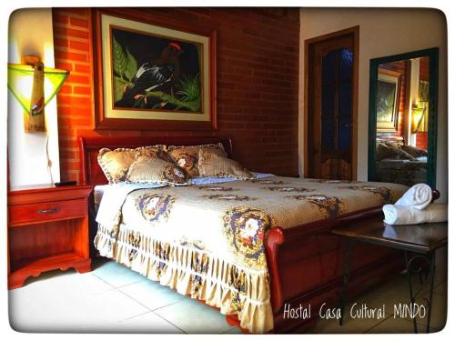 a bedroom with a bed and a table and a picture at Casa Cultural Mindo in Mindo