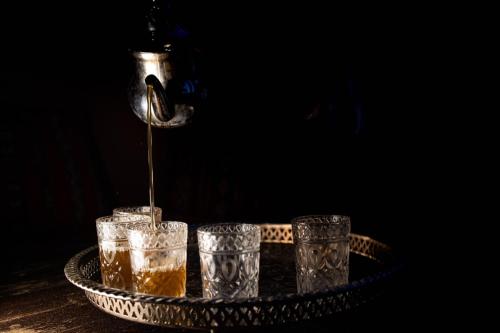a drink being poured into three glasses on a tray at M'hamid Bivouac - Chez Naji in Mhamid