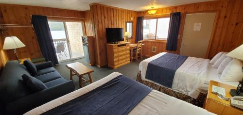 a hotel room with two beds and a chair and a television at The Lake Motel in Lake George
