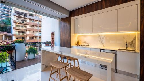 cocina con encimera y 2 taburetes en PIER 57 - 509 Unique 2 BR Condo Romantic Zone, en Puerto Vallarta