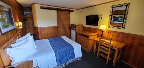 a bedroom with a bed and a desk and a television at The Lake Motel in Lake George