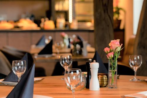a table with wine glasses and a vase of flowers at Hotel auszeit Neunkirchen-Seelscheid in Neunkirchen