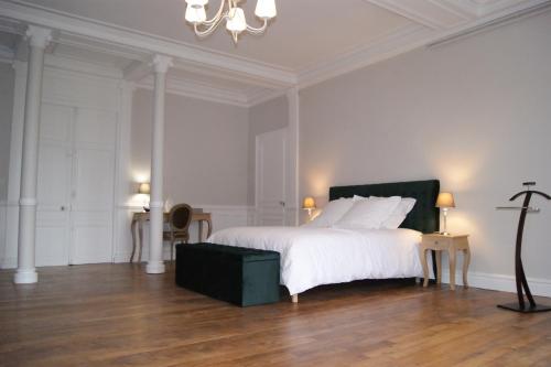 una camera bianca con un grande letto e un lampadario a braccio di Gite la chaumière Le chateau de la Brosse a Brinay