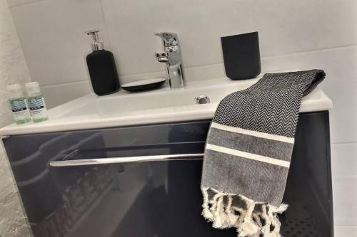La salle de bains est pourvue d'un lavabo et d'une serviette noire et blanche. dans l'établissement Vue incroyable sur Vannes à deux pas des remparts, à Vannes