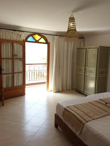 a bedroom with a bed and a large window at ESCALE PARADIS 10 pers 4 ch 3 sdb piscine in Aourir