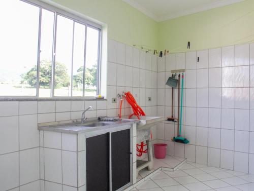 a white tiled bathroom with a sink and a window at Apartamento São Pedro SP in São Pedro